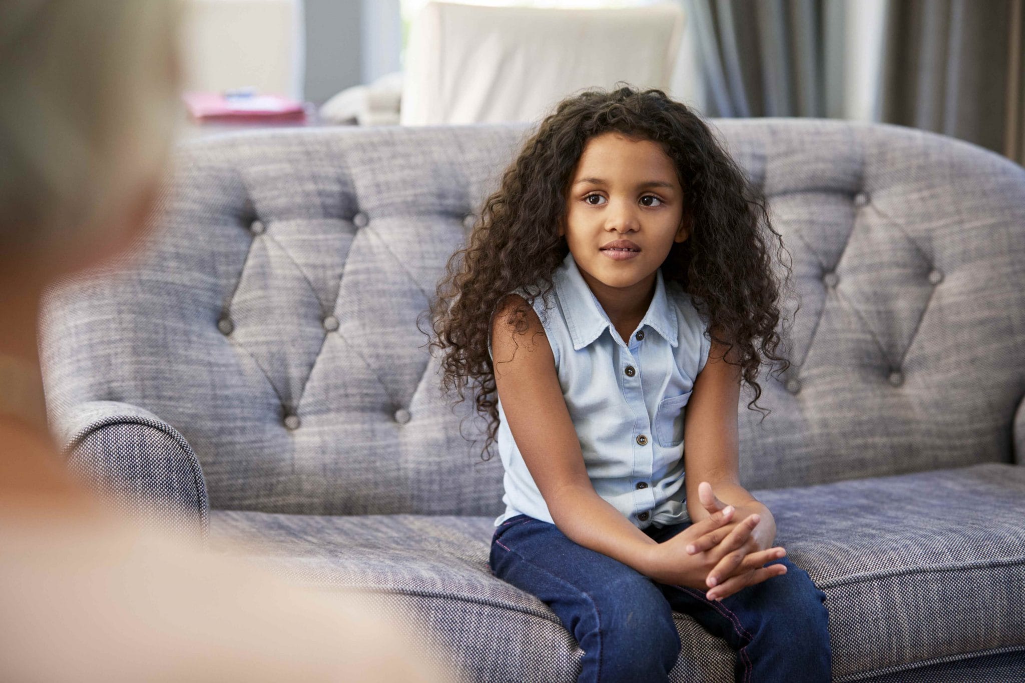 child sitting on couch during therapy session speaking with mental health therapist