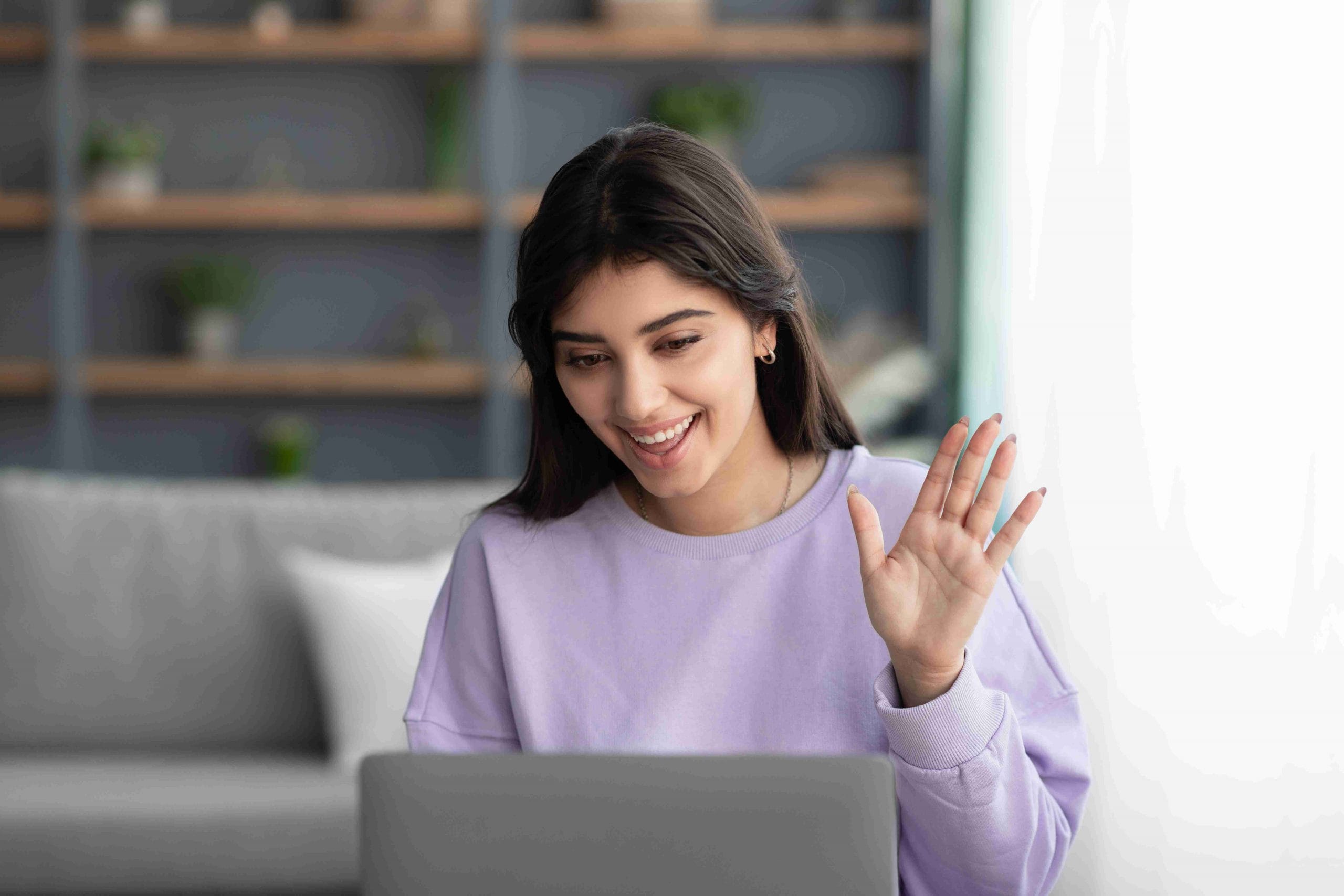 Woman waving during her Telehealth therapy session