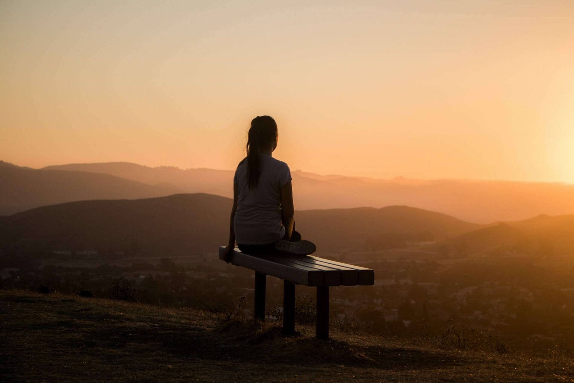Woman sitting on a bench watching the sun set